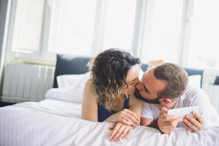 a man and a woman talking intimately and kissing on a bad