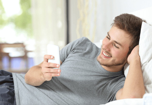 a guy reading a flirtatious text message on his cell phone