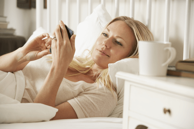 woman laying in bed texting a guy