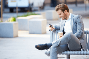 a guy texting sitting on a bench
