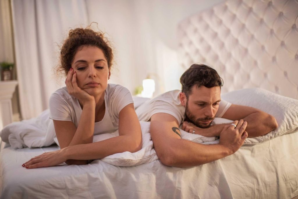 unhappy couple laying on a bed